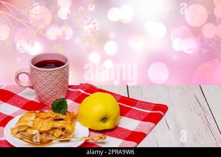 Ein Stück hausgemachter frischer Apfelstrudel mit einer Tasse Kaffee und einem frischen Apfel auf rotem Picknicktuch vor abstraktem Frühlingshintergrund. Concept Morgenkaffee. Leerzeichen. Stockfoto