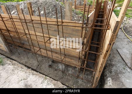 Festgeknüpfte Stütze und montierte Schalung aus der Nähe vor dem Ausgießen des Streifenfundaments beim Bau eines Hauses Stockfoto