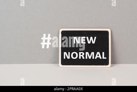 Die Wörter New Normal mit Hashtag stehen auf einem schwarzen, grauen Hintergrund Stockfoto