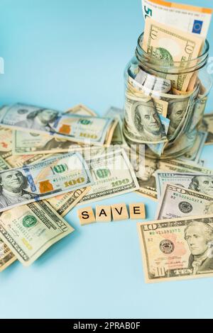 Geld in internationaler Währung, einschließlich des Euro, liegt der Dollar auf blauem Hintergrund neben einem Glas mit Banknoten und der Inschrift außer. Stockfoto