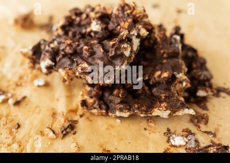 Nahaufnahme von Erdnussbutter, Puffreis und Schokolade, sehr leckeres selbstgemachtes Dessert, Dessertscheiben auf Pergament. Stockfoto