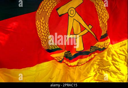 Ein Stück der Flagge der ehemaligen DDR mit Emblem, Hammer, Kompass, Ohrenkranz. Stockfoto