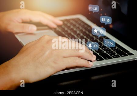 Social Media und Marketing virtuelle Symbole Bildschirm Konzept.Geschäftsmann Tastatur mit Laptop-Computer auf dem Schreibtisch eingeben. Stockfoto