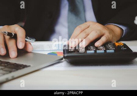 Businessman Holding Taschenrechner und Geschäftsdokumente Charts statistische Daten Investitionsanalyse und Steuerbuchhaltung. Stockfoto