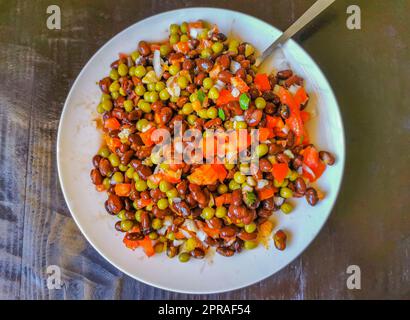 Gemüseteller mit Karotten Erbsen Zwiebeln Bohnen auf weißem Teller. Stockfoto