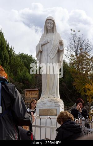 Statue der Jungfrau Maria, Königin des Friedens, auf dem Berg Podbrdo, umgeben von betenden Pilgern. Medjugorje, Bosnien und Herzegowina. Stockfoto