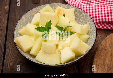 In Scheiben geschnittene Melonenstücke auf einem runden grauen Teller auf dem Tisch Stockfoto