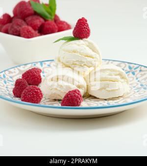 Vanilleeiskugeln mit roten Himbeeren auf einem runden Teller Stockfoto