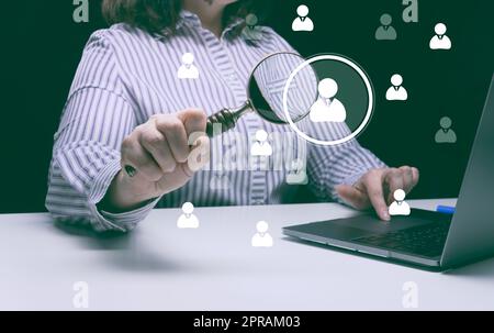 Eine Frau im Anzug sitzt an einem Tisch und arbeitet an einem Computer Stockfoto