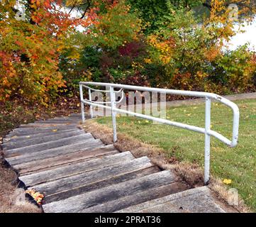 Die gebogenen hölzernen Stufen führen nach unten und verbinden sich mit dem Weg rund um den Fort Patrick Henry Dam. Herbstlaub mit Farbpfad. Stockfoto