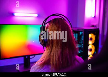 Happy Gamer Endeavor spielt ein Online-Videospielturnier mit Neonlichtern am Computer Stockfoto