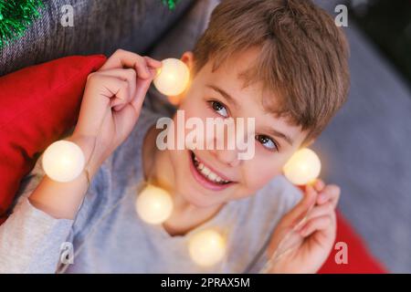 Nahaufnahme eines Weihnachtskindes mit Weihnachtslichtern in den Händen Stockfoto