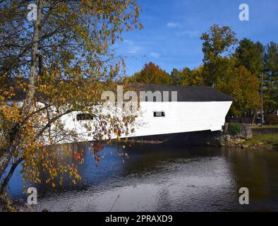 Elizabethton Covered Bridge, Elizabethton, Tennessee, erstreckt sich über den Doe River. Herbst färbt Bäume in Orange und Gold. Brücke wird reflektiert Stockfoto