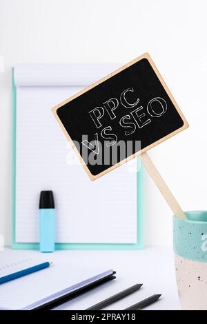 Textunterschrift für PPC vs. Seo. Konzept bedeutet Bezahlung pro Klick im Vergleich zu Suchmaschinenoptimierungsstrategien kleines Blackboard mit wichtiger Nachricht in Cup on Desk mit Zwischenablage. Stockfoto