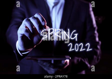 Konzeptionelle Überschrift Frühjahr 2022. Geschäftsübersicht Jahreszeit, zu der die Blumen nach der Wintersaison steigen Hand mit Stift zeigt wichtige Infortationen mit anderem Tablet Stockfoto