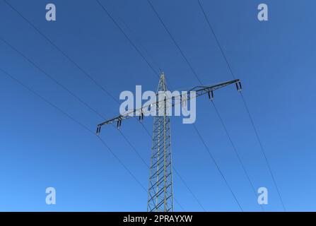 Ansicht sehr großer Strommasten mit Hochspannungskabeln von einem fahrenden Auto. Stockfoto