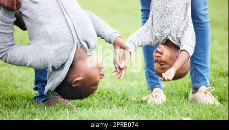 Spielen ist der Eingang in die Kinderherzen. Zwei Kinder hängen von ihren Eltern draußen auf dem Kopf. Stockfoto