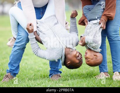 Spaß macht die Abwesenheit von Stress. Zwei Kinder hängen von ihren Eltern draußen auf dem Kopf. Stockfoto