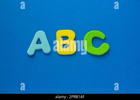 Schulbettlerinnen. ABC-farbige Buchstaben auf blauem Hintergrund, Kopierbereich. Englisch für Anfänger mit Kopierbereich. Stockfoto