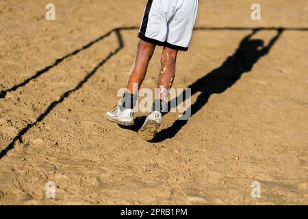 Ein junger afro-kolumbianischer Fußballspieler schwingt während eines Trainings in Necoclí, Antioquia, Kolumbien, an der Kreuzung eines Tores. Stockfoto