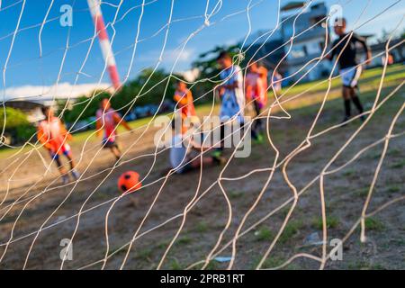 Ein junger afro-kolumbianischer Fußballspieler erzielt das Tor während eines Trainings in Necoclí, Antioquia, Kolumbien. Stockfoto