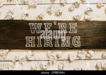 Textzeichen mit „We Re are hire“ (Wir stellen ein). Word for Advertising Employment Workforce Placement New Job wichtige Ideen, die auf einem Holzstück mit Papierwickeln auf dem Boden geschrieben wurden. Stockfoto