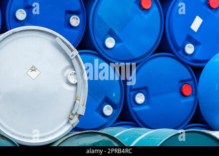 Alte Chemiefässer. Blaue und grüne Ölfass. Öltank aus Stahl und Kunststoff. Lager für giftige Abfälle. Gefahr Chemikalienfass mit Warnschild. Industrieabfälle in Fass. Lagerung von gefährlichen Abfällen im Werk. Stockfoto