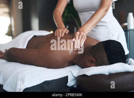 Heilen Sie Ihre schmerzenden Muskeln mit einer Rückenmassage. Ein junger Mann bekommt eine Rückenmassage in einem Spa. Stockfoto