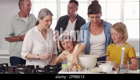 Ein paar Eier knacken, um einen Kuchen zu backen. Eine Familie, die zusammen in der Küche backt. Stockfoto