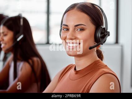 Jeder Anruf ist eine weitere Möglichkeit, zu helfen. Beschnittenes Porträt einer attraktiven jungen Callcenter-Agenten, die an ihrem Laptop arbeitet. Stockfoto
