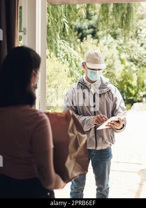 Kein Grund, das Haus zu verlassen. Ein junger Mann, der einem Kunden zu Hause ein Paket liefert. Stockfoto