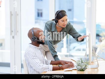 Wenn Sie einfach hier klicken, sollte es erscheinen. Eine junge Geschäftsfrau, die ihrem männlichen Arbeitskollegen hilft. Stockfoto