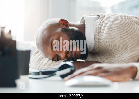 Ich bin zu erschöpft, um zu arbeiten. Ein hübscher junger Geschäftsmann schläft tagsüber auf seinem Schreibtisch. Stockfoto