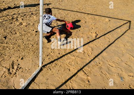 Ein junger afro-kolumbianischer Torwart rettet den Schuss während eines Fußballtrainings in Necoclí, Antioquia, Kolumbien. Stockfoto