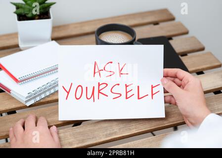 Schreiben Text anzeigen Frag dich selbst. Geschäftsansatz über die zukünftige Bedeutung und den Zweck des Lebens nachdenken sitzende Geschäftsfrau, die wichtige Botschaft auf Papier auf dem Tisch hält. Stockfoto