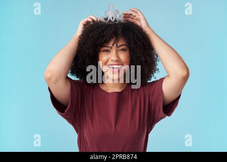 Was ist eine Königin ohne ihren König noch mächtiger. Studioaufnahme einer jungen Frau, die ihren Kopf auf einen blauen Hintergrund stellt. Stockfoto