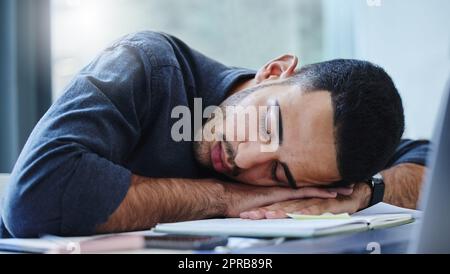 Schieben Sie sich nie zu einem Burnout. Ein junger Geschäftsmann fühlt sich erschöpft und schläft auf seinem Schreibtisch in seinem Büro. Stockfoto