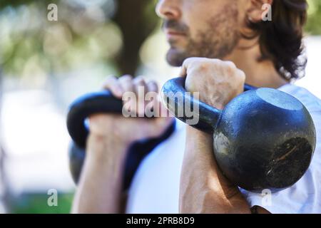 Alles über die Gewinne. Ein unkennbarer Mann trainiert mit seinen Hanteln draußen im Park. Stockfoto