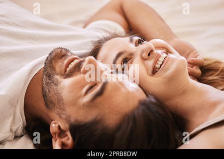 Blicken Sie an die Decke und machen lahme Witze. Ein junges Paar, das zu Hause einen intimen Moment auf dem Bett hat. Stockfoto