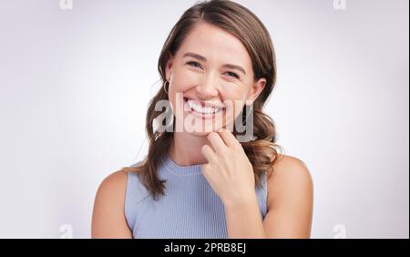 Es gibt immer einen Grund zu lächeln - finden Sie es. Studioportrait einer glücklichen jungen Frau, die vor grauem Hintergrund posiert. Stockfoto