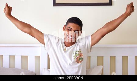 Erhebt euch und glänzt schlafend. Ein hübscher junger Mann sitzt im Bett und dehnt sich in den frühen Morgenstunden. Stockfoto