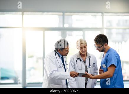 Team oder Gruppe von Ärzten, Krankenschwestern und medizinischem Fachpersonal, die sich in einem Krankenhaus unterhalten, treffen und über das Gesundheitswesen diskutieren. Praktizierende in Labormänteln sehen sich in einer Klinik Akten auf einem Tablett an Stockfoto