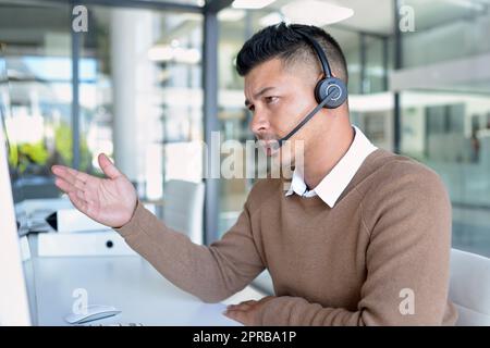 Lassen Sie mich die Optionen für Sie durchgehen... einen jungen Call Center-Agenten, der in einem Büro arbeitet. Stockfoto