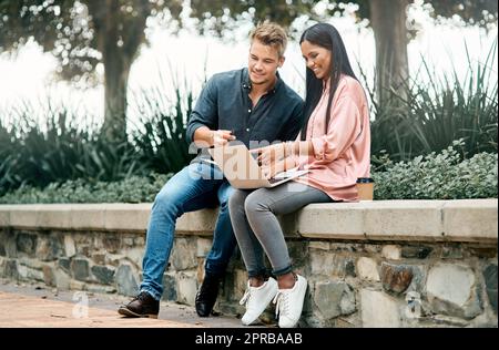 Vergessen Sie den Fehler, erinnern Sie sich an die Lektion. Zwei junge Studenten mit einem Laptop, während sie draußen auf dem Campus sitzen. Stockfoto