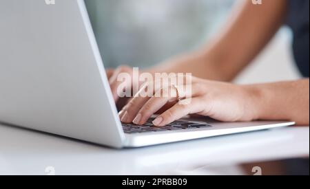 Senden von Statusaktualisierungen an Clients per E-Mail. Nahaufnahme einer unkenntlichen Geschäftsfrau, die in einem Büro einen Laptop benutzt. Stockfoto