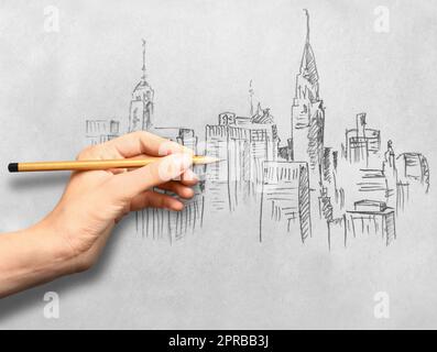 Eine Frau, die eine Skizze der Stadt zeichnet, mit Graphitstift auf weißem Papier, Nahaufnahme Stockfoto