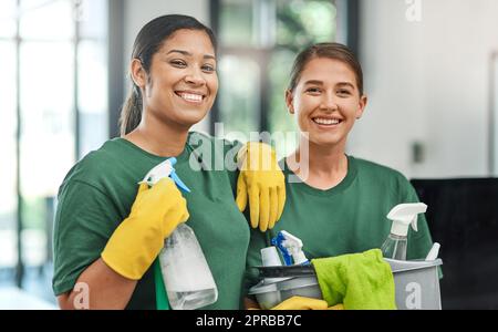 Das beste Team, um Ihr Büro sauber zu halten. Porträt von zwei jungen Frauen, die ein modernes Büro putzen. Stockfoto