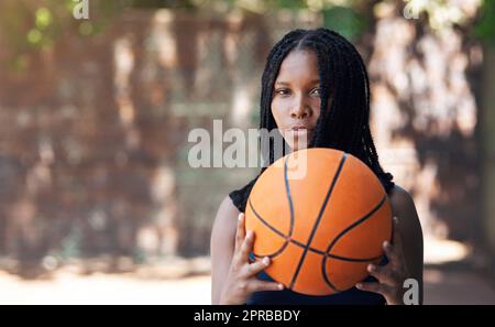 Kommen Sie mich an. Beschnittenes Porträt einer attraktiven jungen Sportlerin, die auf dem Basketballfeld steht. Stockfoto