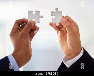 Es kommt jetzt alles zusammen. Zwei unkenntliche Geschäftsleute vervollständigen ein Puzzle. Stockfoto