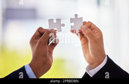 Die Antwort liegt zwischen uns. Zwei unkenntliche Geschäftsleute, die ein Puzzle vollenden. Stockfoto